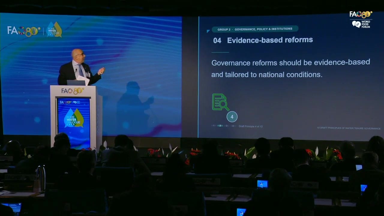 Stephen Hodgson at the lectern in FAO's Plenary Hall, with the slide on draft principle 4, evidence-based reforms