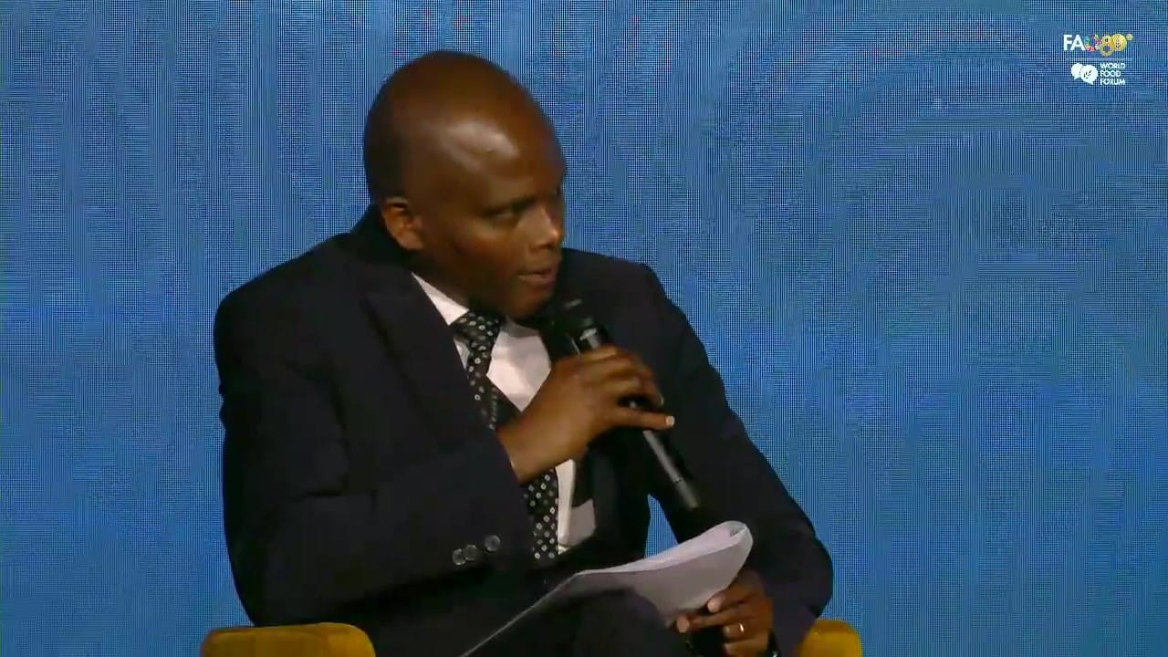 Daniel Mwendah M'Mailutha speaking into a microphone, holding notes